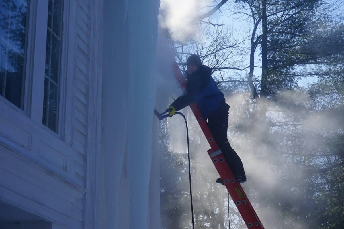 Person removing ice from a roof